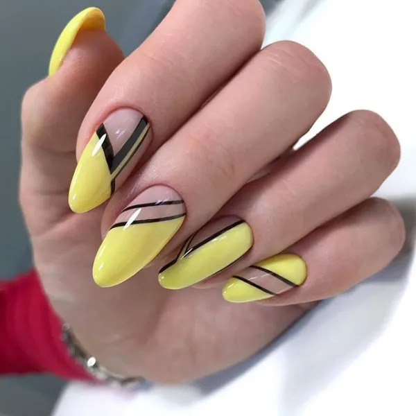 Uñas geométricas con fondo rosa y formas en negro y amarillo